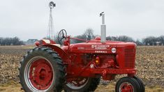 an old red farmall tractor parked in a field