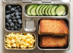 a lunch box with sandwiches, blueberries and cucumbers