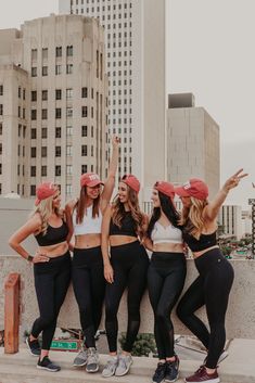 four girls in matching sports bras and red caps are posing for the camera