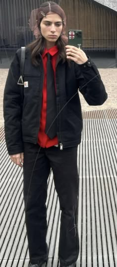 a man in black jacket and red shirt taking a selfie with his cell phone