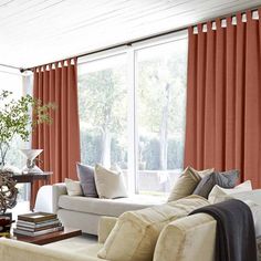 a living room with red curtains and white furniture in front of a large window filled with windows