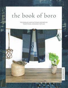 the book of boro is on display next to a potted plant and some cloths