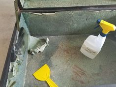 an open suitcase filled with cleaning supplies on top of a carpeted floor next to a yellow spatula