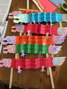 paper dragon puppets on sticks with words written on them and some scissors next to them