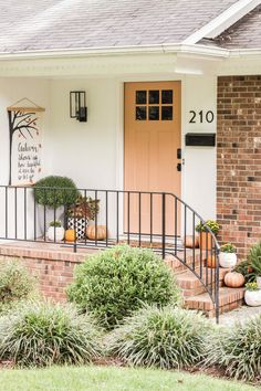 the front porch is decorated with pumpkins and greenery