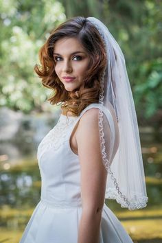 a woman in a wedding dress is posing for a photo with her veil over her head