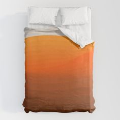 an orange and yellow bed with two pillows on it's sides, in front of a white wall