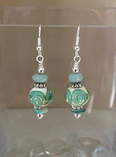 Beautiful spiral motif green blue aqua lampwork bead earrings. Lovely short dangle drop style earrings that are great for everyday or evening. These are lovingly handcrafted using components from both salvaged jewelry, new accent beads and findings. Packaged on display card in an eco-friendly box with silicone backings to hold secure. Earring hooks are silver-plated.  I take old jewelry and break down the components to be reused in new jewelry pieces, a process that is Earth-friendly, leading to lower waste --not to mention it is lots of creative FUN! I try my best to capture true colors, but please keep in mind that your computer settings can affect how they appear. If you have any questions or concerns please feel free to message me. Green Spiral Earrings As Gift, Summer Green Earrings With Dangling Beads, Green Dangle Earrings With Colorful Beads, Green Polished Bead Earrings, Simple Bead Earrings, Green Recycled Glass Dangle Earrings, Blue Glass Earrings With Dangling Beads, Bead Drop Earrings, Lampwork Bead Earrings