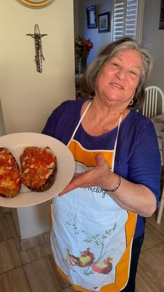 an older woman holding a plate with two pieces of pizza on it