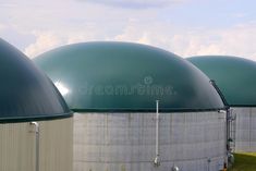 three large round tanks are lined up in front of each other on a cloudy day