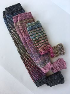 three pairs of knitted mittens sitting next to each other on a white surface