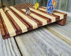 a wooden cutting board sitting on top of a wooden table next to a bottle opener