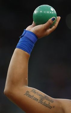 a woman holding a green ball in her right hand while wearing a blue shirt and wrist band