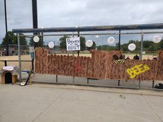 a fenced in area with signs and other items on the fence, including a sign that says bee's