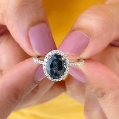 a woman's hands holding a ring with a blue stone