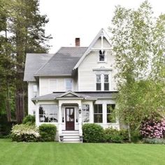 a large white house sitting on top of a lush green field