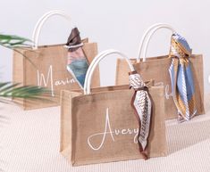 three small bags with ties on them are sitting on a table next to a plant