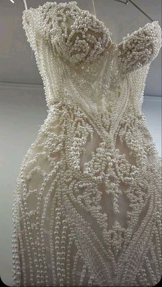 a white wedding dress hanging on a clothes line with pins in it's back