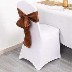 a white chair with a brown bow on it and a wine glass sitting next to it