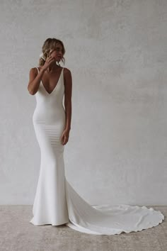 a woman in a white wedding dress posing for the camera with her hand on her face