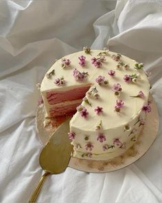 a white cake with pink flowers on it and a slice taken out of the cake