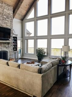 a living room with large windows and a stone fireplace