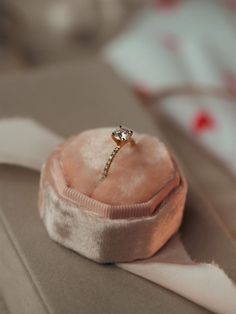 an engagement ring sitting on top of a pink velvet box