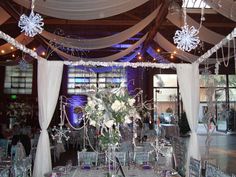 an indoor wedding venue with white drapes and chandelier draped over the tables