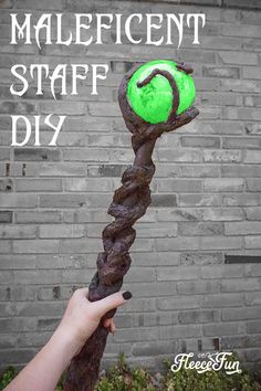 a hand holding a stick with a green ball on it and the words, maleficent staff diy