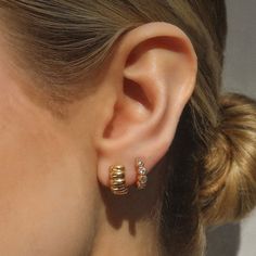 a close up of a woman's ear wearing gold and white diamond studs