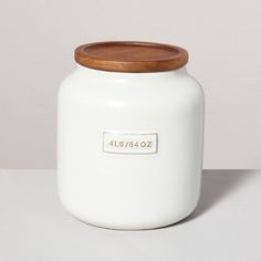 a white jar with a wooden lid sitting on a table