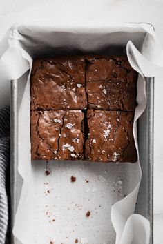 chocolate brownies in a baking tin with parchment paper on the side and white napkins next to them