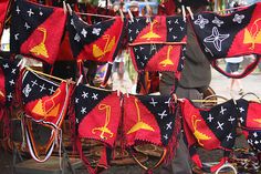 there are many red and black blankets hanging on the clothes line in front of people