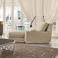 a living room filled with lots of furniture next to a large white window covered in curtains