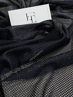 a label on the back of a black mesh material with small white dots in it