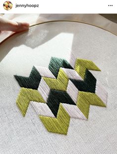 someone is stitching something in the shape of an arrow with green and yellow strips