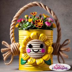 a yellow flower pot with flowers in it and a rope hanging from the handle that has a smiling face on it