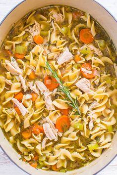 a pot filled with chicken noodle soup on top of a wooden table