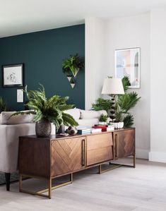 a living room filled with furniture and potted plants on top of a wooden table