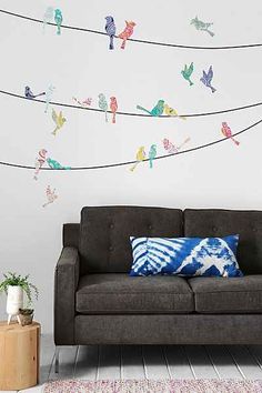 a couch sitting in front of a white wall with birds on the wires above it