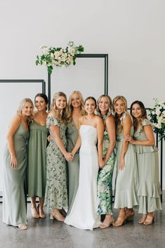 a group of women standing next to each other in front of a wall with flowers