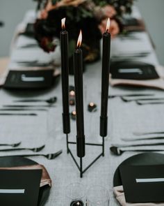 the table is set with black candles and place settings for two people to sit at