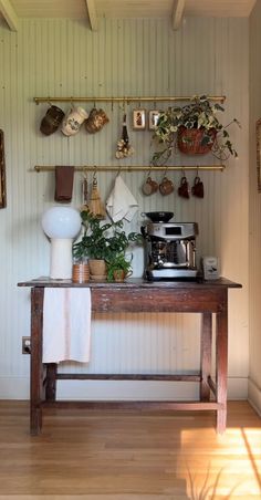 Farm house coffee bar | Brown wooden table with plants on table | Breville coffee machine | Cups hanging from golden bar Kaffe Station, Coffee Bar Cart, Coffee Bar Station, Diy Coffee Bar, Home Coffee Stations, Coffee Nook, Home Coffee Bar, Coffee Bar Home, Coffee Carts