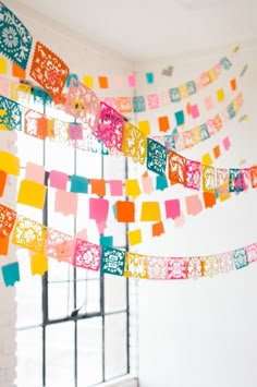 colorful paper streamers hanging from the ceiling in front of a window with windowsills