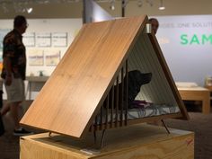 a dog in a bed made out of wood with people walking around the room behind it