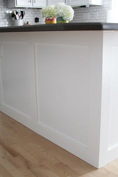 a kitchen island with white cabinets and black counter tops in front of a brick wall