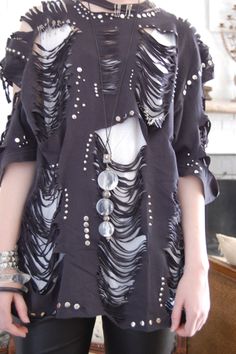 a woman standing in front of a mirror wearing black pants and a top with feathers on it