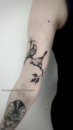 a woman's arm with a bird and flower tattoo on the left side of her arm