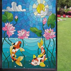 a stained glass window with two koi fish swimming in the water and lily pads