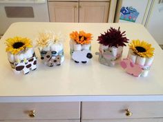 four small vases with fake sunflowers in them sitting on a kitchen counter